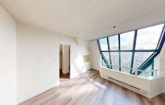 an empty apartment with a large window and hardwood floors
