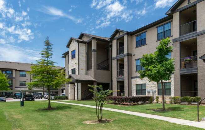 A sunny day at a residential complex with apartment buildings and green lawns.