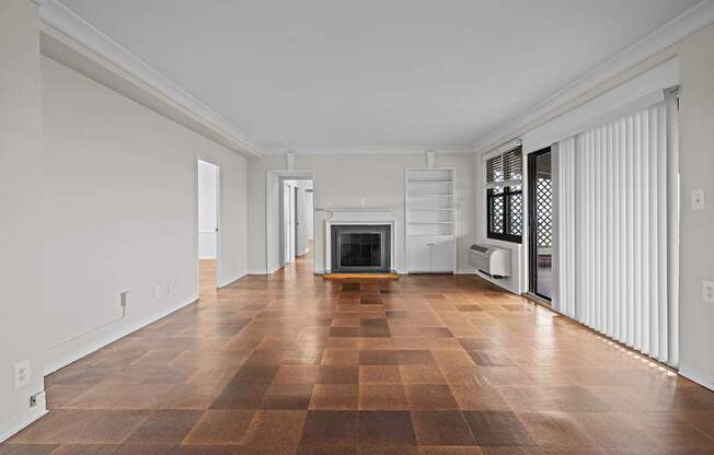 A large empty room with a fireplace and wooden floors.