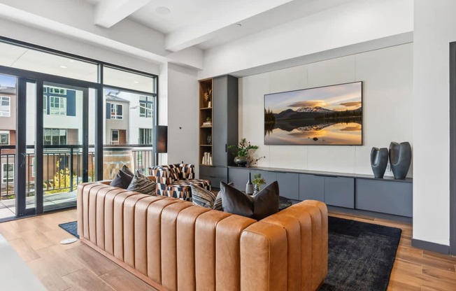 A living room with a brown sofa and a large painting on the wall.