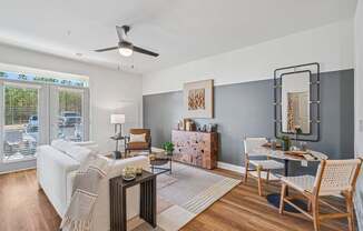 A living room with a white couch, a wooden coffee table, and a dining table set up.