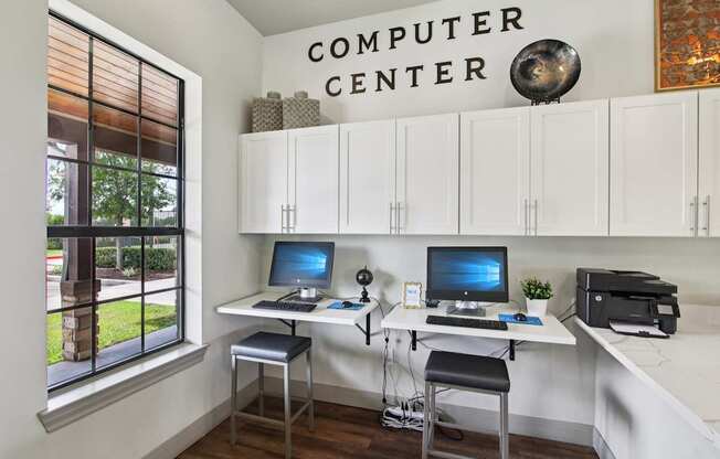 A computer center with two computers and a printer.