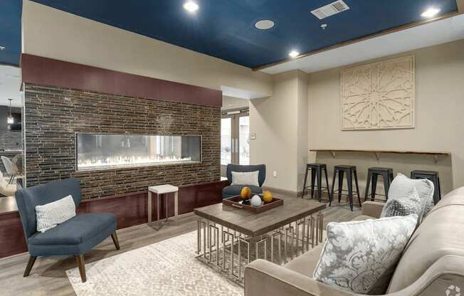 A living room with a stone fireplace and a grey sofa.
