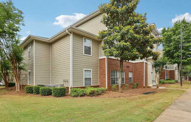 A residential building with a beige exterior and a brick section on the side.