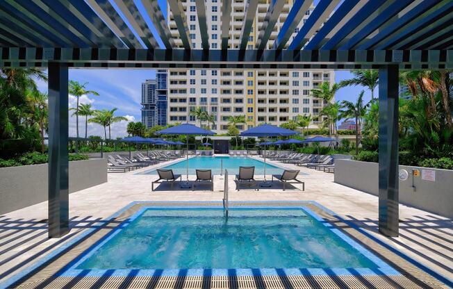 a swimming pool with lounge chairs and umbrellas in front of a building at Regatta at New River, Fort Lauderdale, 33301