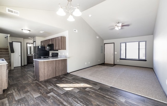 A spacious living room with a kitchen area in the background.