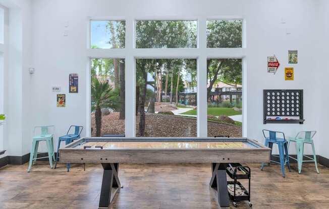 a pool table in a room with windows and a view of a park