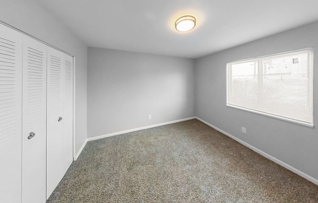 an empty bedroom with a window and a closet