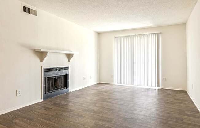 A large, empty room with a fireplace and wooden floors.