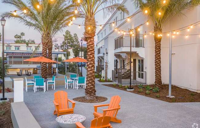 A patio with orange chairs and palm trees.
