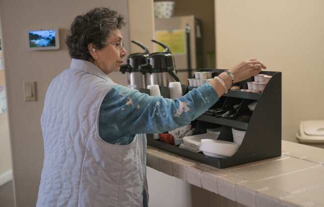 a woman prepares food in a kitchen on a laptop