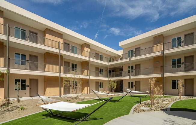 A sunny day at a modern apartment complex with a hammock in the courtyard.