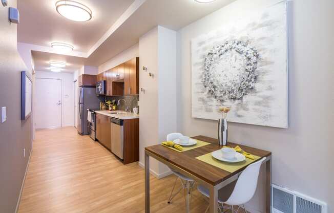 a dining room and kitchen with a table and chairs and a painting