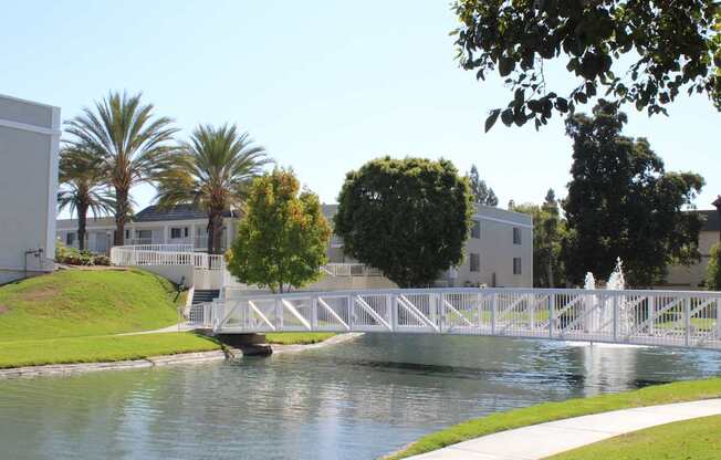A white bridge over a body of water with a white fence and a white building in the background.