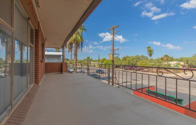 A balcony with a view of a parking lot and palm trees.