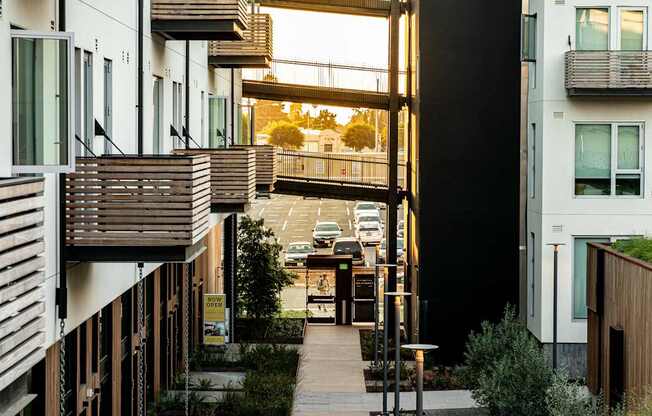 A long, narrow walkway between two buildings with a metal railing on the left and a wooden railing on the right.