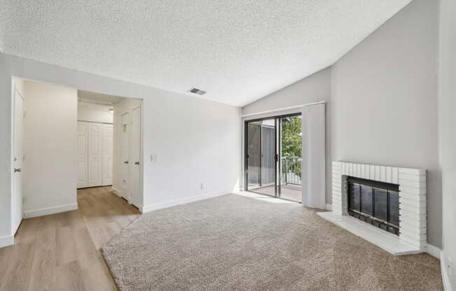 an empty living room with a fireplace and a sliding glass door