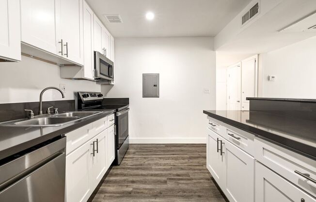 A kitchen with white cabinets and a wood floor.