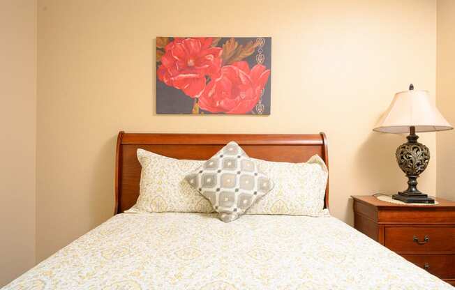 a bedroom with a bed and a nightstand with a lamp at Oak Terrace Senior Apts, Hemet, CA 92543