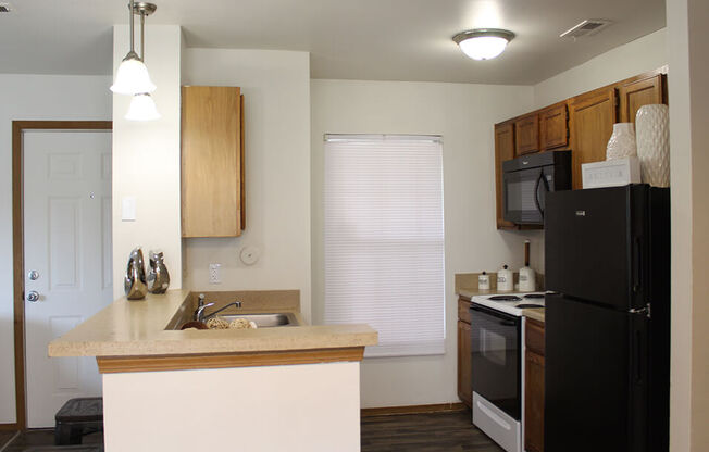 a kitchen with a black refrigerator freezer next to a stove top oven