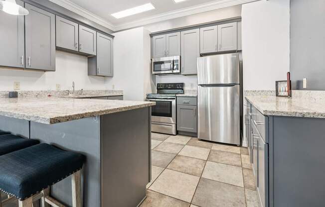 A kitchen with a refrigerator, stove, and bar stools.