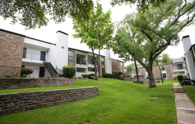 exterior view of apartments with a green lawn and trees