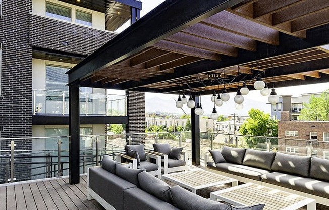 A wooden deck with a grey couch and a black pole.