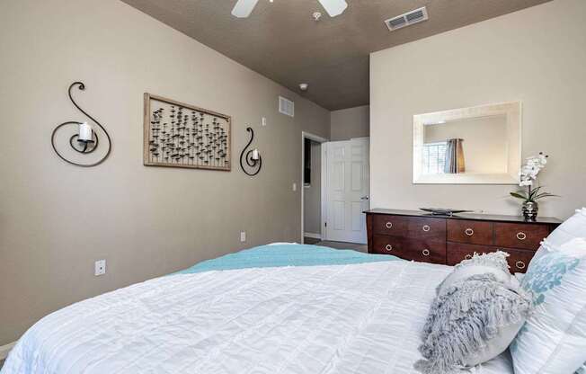 A bedroom with a large bed and a dresser with a mirror above it.