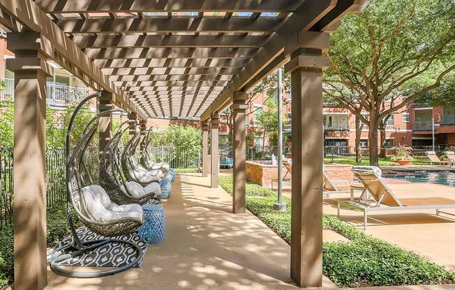 A row of concrete statues are lined up under a wooden pergola.