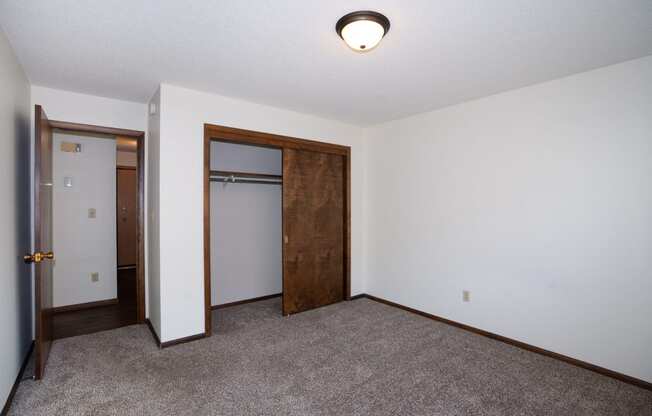 an empty room with carpet and a door to a closet