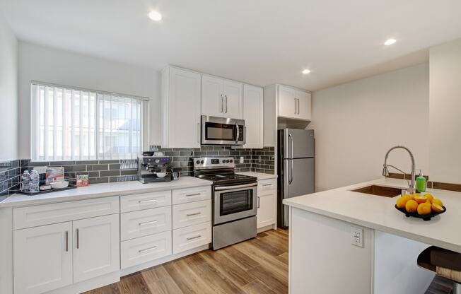 a kitchen with white cabinets and stainless steel appliances