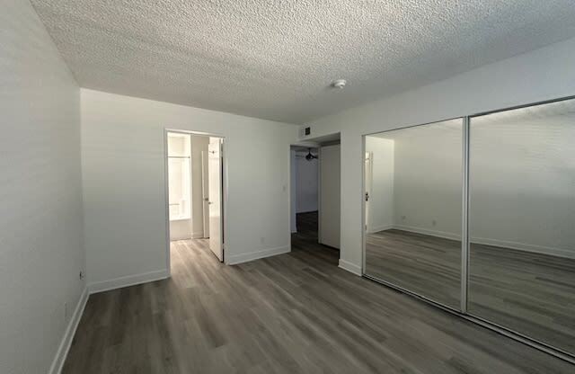 an empty living room with a large mirror and wooden floors