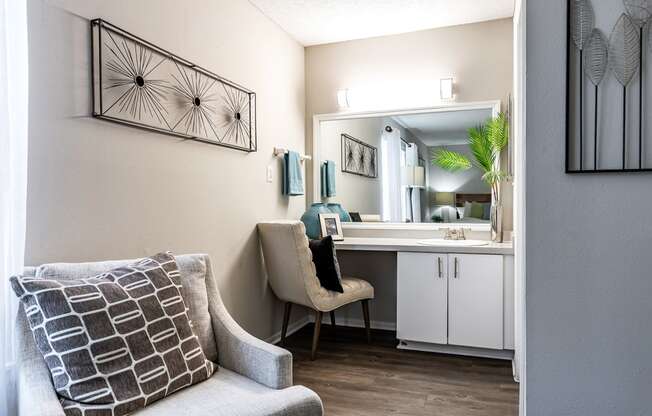 a living room with a couch and a chair next to a bathroom with a sink