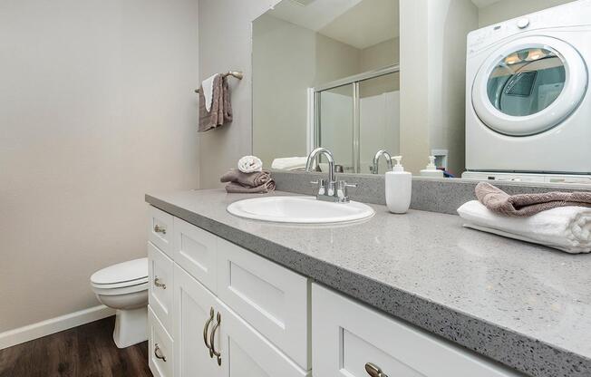 a white sink sitting under a mirror