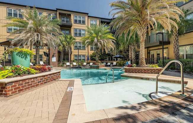 A pool surrounded by palm trees and a brick wall.