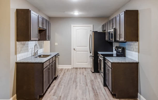 A kitchen with dark brown cabinets and a black refrigerator at Mode at Melbourne, LLC Apartments, Florida, 32901