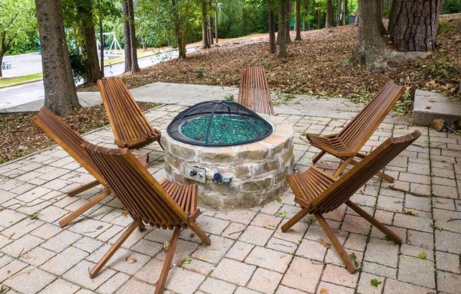 a stone fire pit with wooden chairs around it