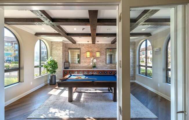a game room with a pool table and a wall of windows