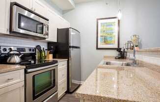 Apartment kitchen with white cabinets and granite countertops at The Pepper Building