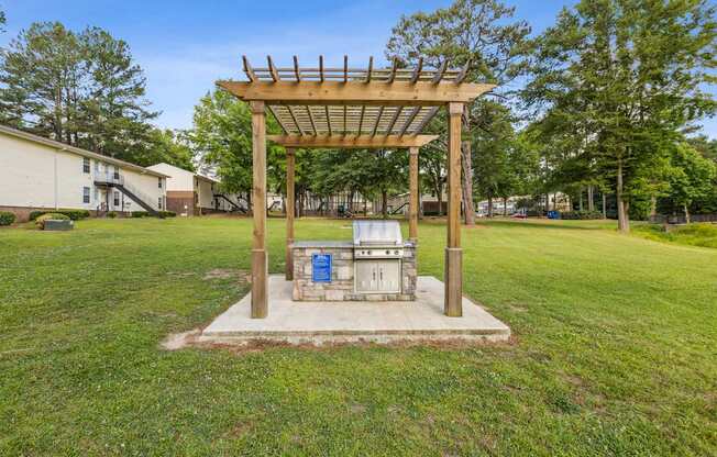 A wooden structure with a roof and a blue door is in the middle of a grassy area.