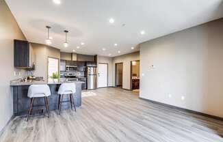 an open kitchen and living room with a kitchen island and bar stools