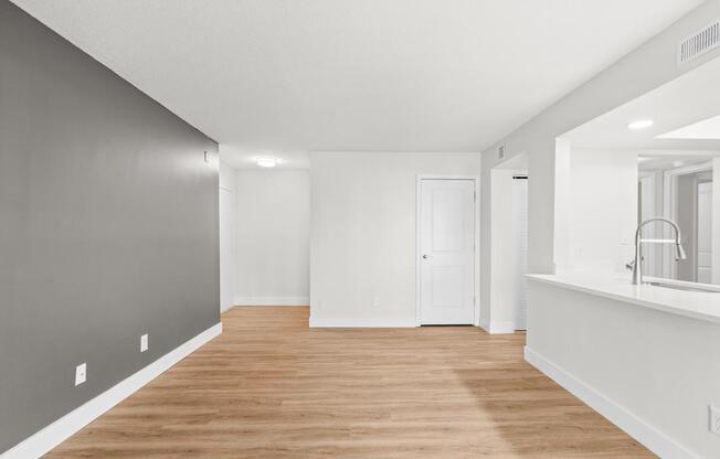 A long, empty room with wooden floors and white walls.