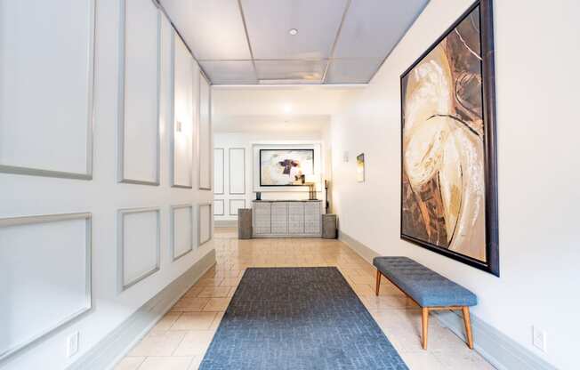 a view down a hallway with a bench and a large painting on the wall at 26 West, Managed by Buckingham Urban Living, Indianapolis