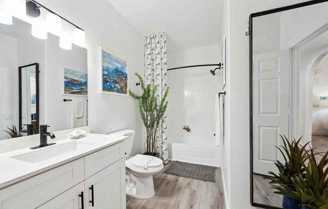 A white bathroom with a toilet, sink, and mirror.