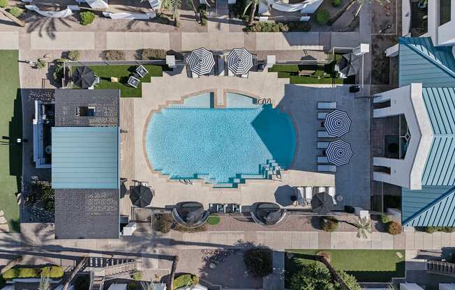 An aerial view of a pool surrounded by palm trees and lounge chairs.