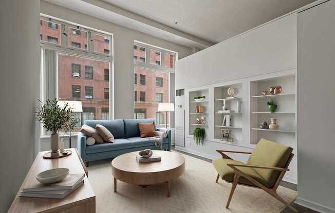 A living room with a blue couch and a green chair at Lowertown Commons Apartments, St. Paul, 55101