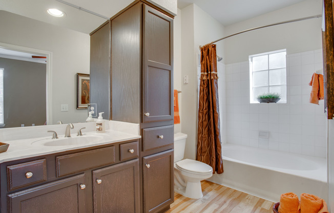 View of Bathroom with Plank-Wood Flooring, Garden Tub, and Storage at Raveneaux Apartments
