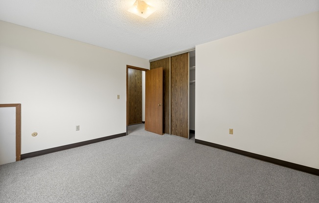 A room with a carpeted floor and two doors.