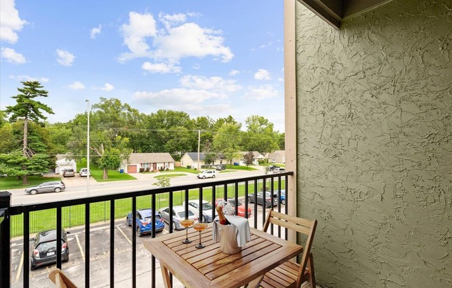 a balcony with a wooden table and chairs and a view of a parking lot