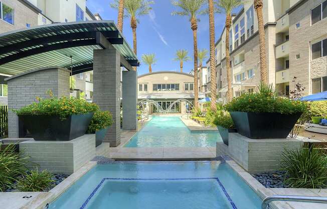 A pool surrounded by plants and palm trees.